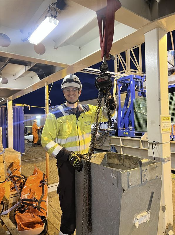 Photo of Andreas Isaksen next to machinery in a work scenario.